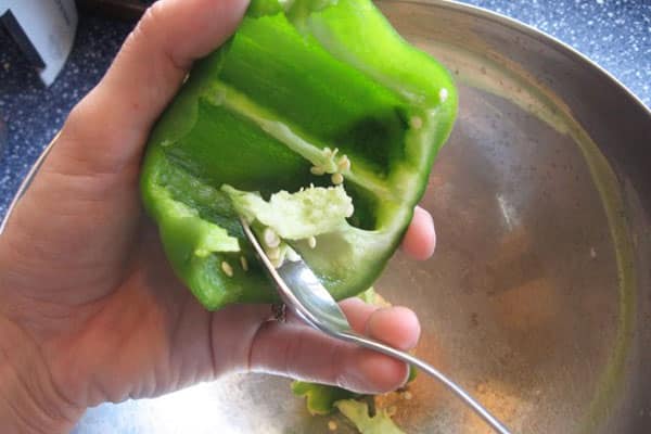 spoon scraping ribs off green pepper