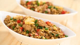 two white bowls with fried rice on wood table