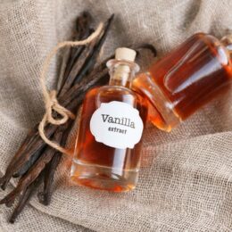 two bottles of homemade vanilla extract and vanilla beans on burlap
