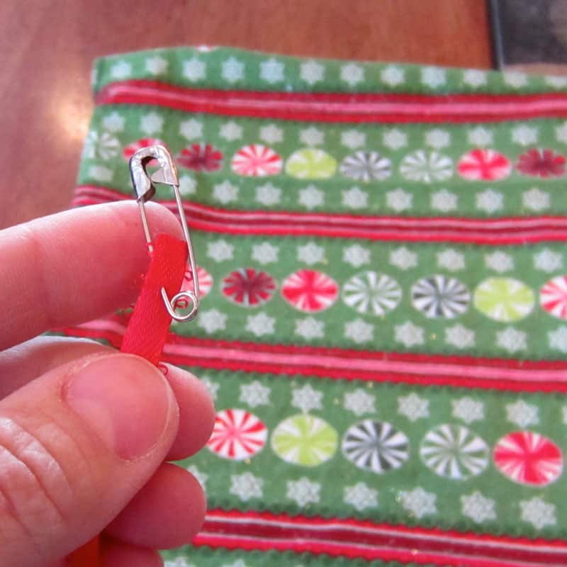 using safety pin to pull ribbon through gift bag