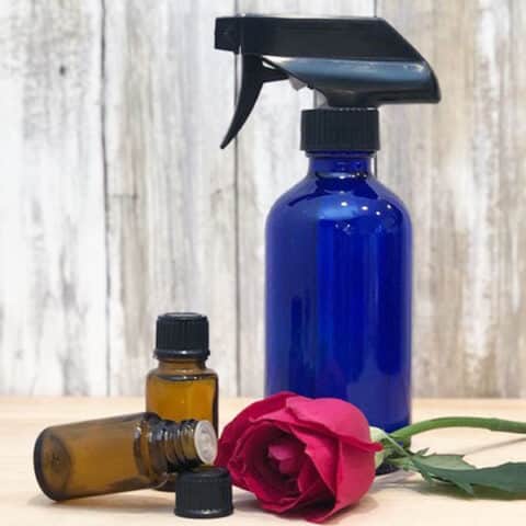 blue glass spray bottle, two essential oil bottles, rose