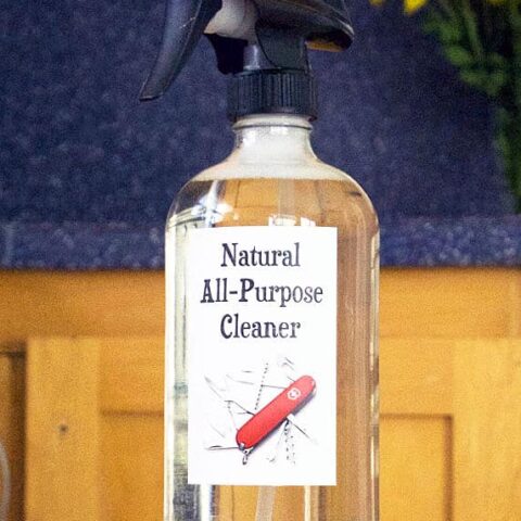 clear glass bottle of cleaner in front of a wooden cabinet
