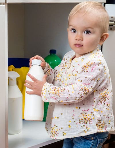 baby opening chemical bottles under sink