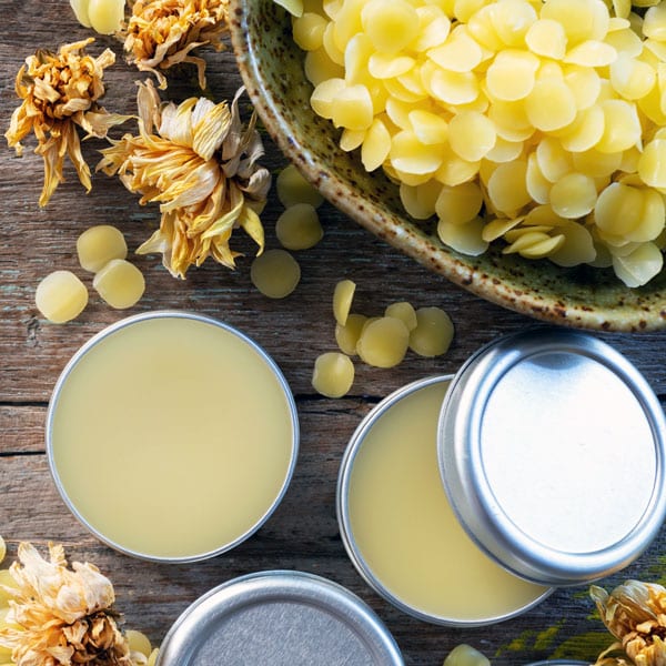 tins of lip balm and beeswax pastilles on wood table