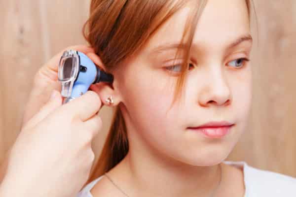 girl having ear examined with otoscope