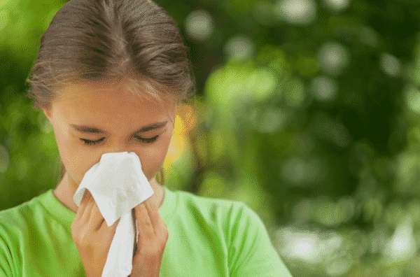 girl sneezing into kleenex