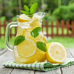 large glass pitcher full of lemonade and lemon slices