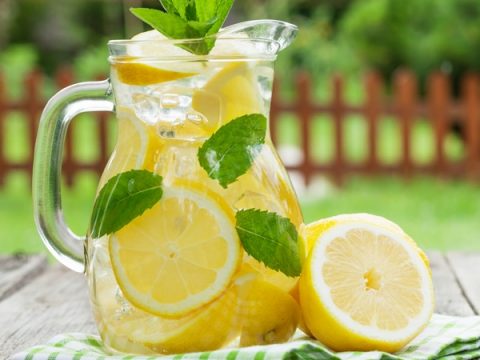 Lemonade. Glass jug with lemonade and lemon slices on a white