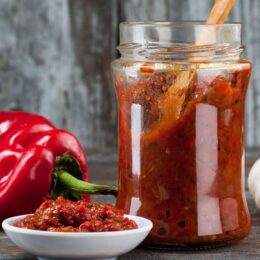 closeup of glass jar with hot sauce and wooden spoon