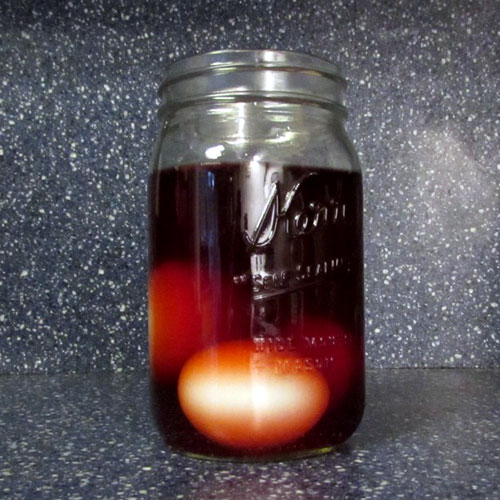 easter egg soaking in jar full of natural dye