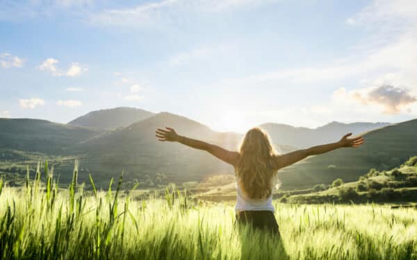 woman in field, arms outstretched