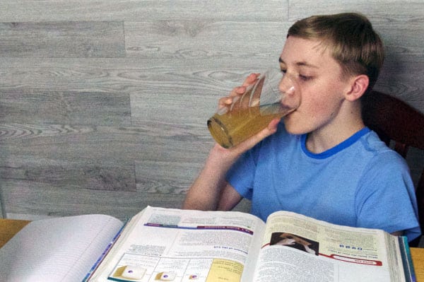 boy doing homework drinking apple juice