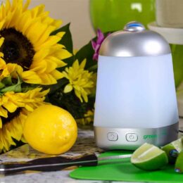 pyramid shaped essential oil diffuser on table with sunflowers and fruit