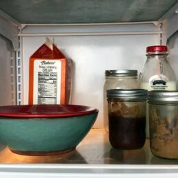bowl in refrigerator covered with plate and two canning jars