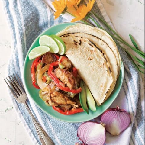 chicken fajitas and tortillas on sea green plate