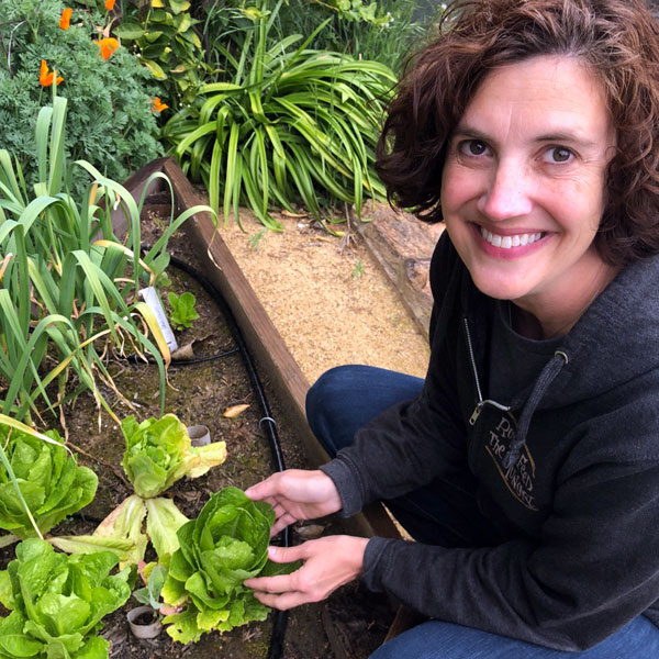 woman smiling in the garden holding a lettuce plant