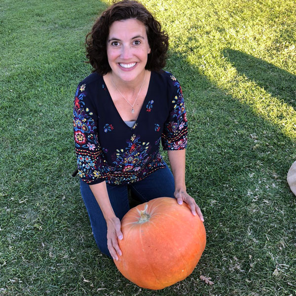 smiling woman on grass holding pumpkin