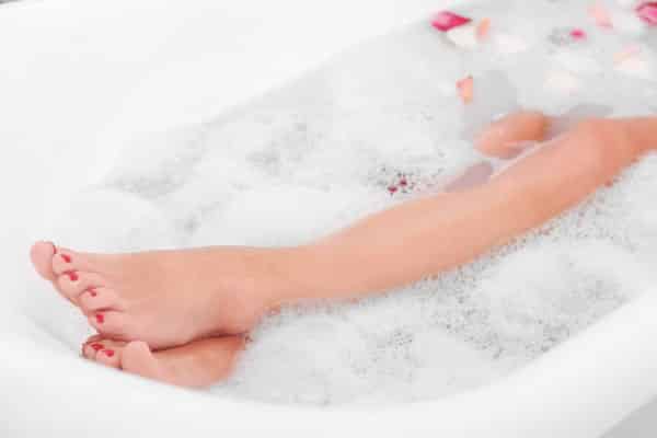 woman in bathtub with rose petals and bubbles on water