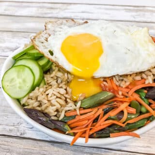 brown rice bowl with vegetables and runny egg over top