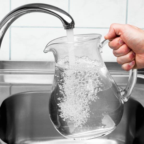 filling glass pitcher at sink
