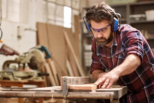 man cutting wood on table saw