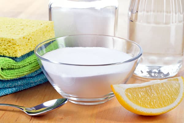 baking soda, vinegar, lemon, cleaning cloths on table