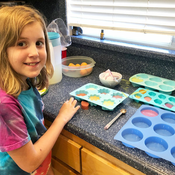 little girl with soap molds on counter